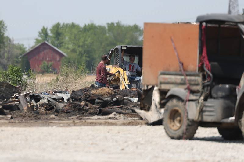 Workers shift through debris after a fire at a horse ranch Wednesday, May 24, 2023, in Beecher.
