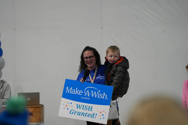 Ashley Montgomery of Mendota (left) announces the granting of Lucas King (right) of Oglesby’s wish to event Attendees at the 2025 Penguin Plunge Saturday, Jan. 25, 2025 at Skydive Chicago in Ottawa.