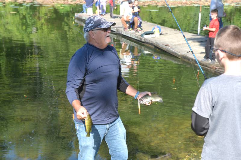 Donald Topp of Sterling, performed his grandfatherly duties when he reached into the water to retrieve two fish caught by his grandsons, Christopher and Avery Holcomb during the Whiteside County Sheriff Office and Mounted Patrol's annual fishing derby at Morrison-Rockwood State Park in Morrison on Saturday, Sept. 9, 2023.