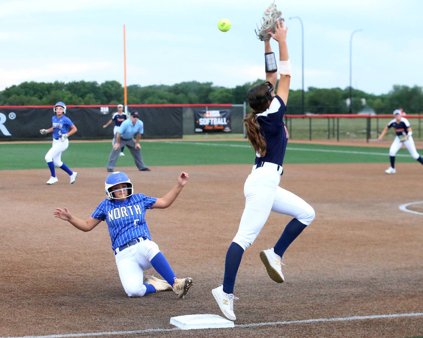 A throw soars over Oswego's Maddie Hernandez head as St. Charles North's Skyla Ritter slides safely into third base during the Class 4A semifinal game on Friday, June 7, 2024 at the Louisville Slugger Sports Complex in Peoria.