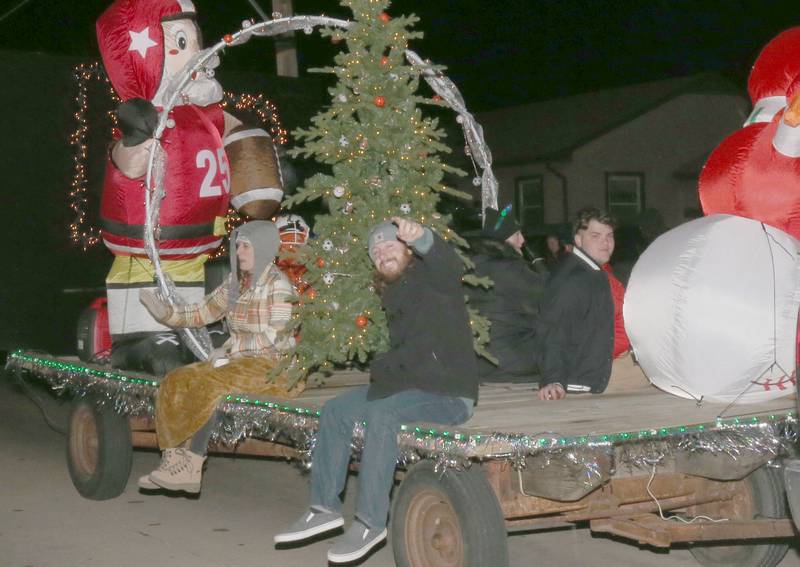 Riders wave on the Locker Room float during the annual Christmas Parade on Saturday, Dec. 7, 2024 on Peoria Street in Peru.