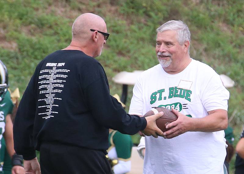 St. Bede head coach Jim Eustice hands William Van Daele class of 1974 alumni the game ball