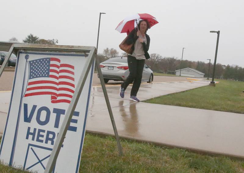 Carrie Lopez holds an umbrella while walking through the rain into a polling place on Tuesday, Nov. 5, 2024 at Hall High School in Spring Valley.