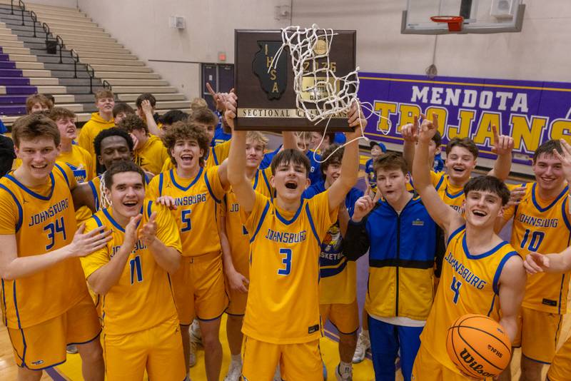 Trey Toussaint lifts the trophy and shouting in celebration with teammates and fans after winning the IHSA 2A Sectional Championship game on March 6, 2026 at Mendota High School.