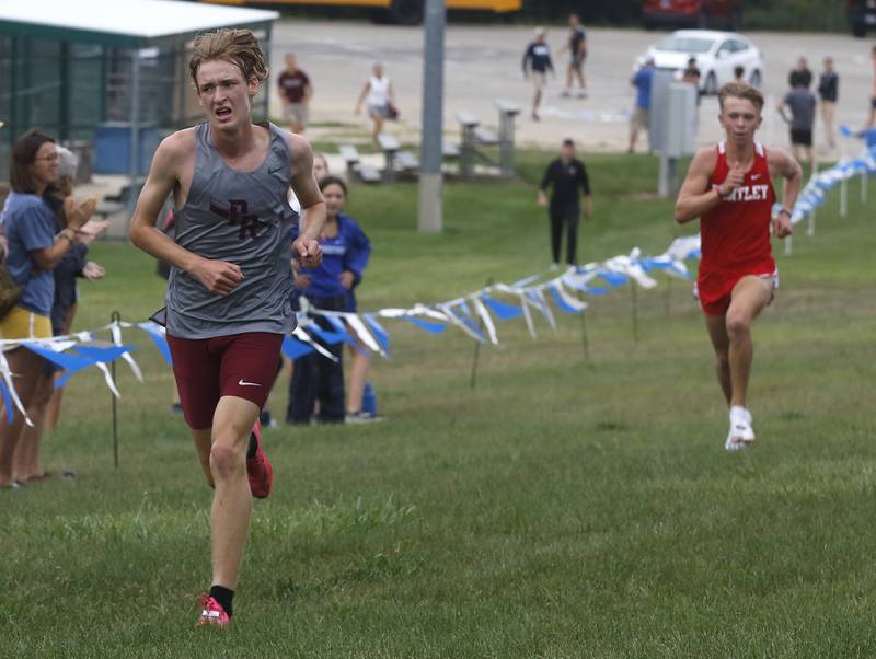 Prairie Ridge’s Will Gelon runs to the finish line in front of Huntley’s Zachary Zuzzio during the boys race of the McHenry County Cross Country Meet Saturday, August 27, 2022, at Emricson Park in Woodstock.