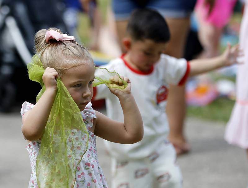 Mia Maiorano, 3, of Crystal Lake, plays peek-a-boo- with a scarf as she listen to the music of the Being Bilingual Rocks (BBR) Band during the Crystal Lake Park District and Public Library's Summer Singalong for Kids on Friday, June 21, 2024, at Crystal Lake's Main Beach.