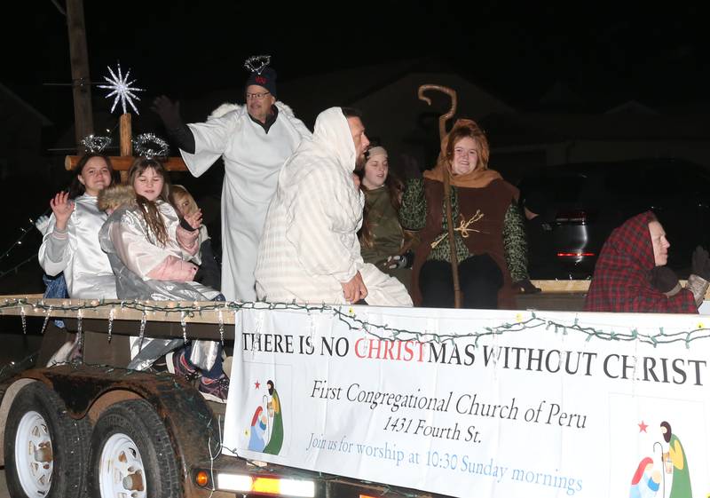 First Congregational Church of Peru members wave as they ride on a float during the annual Christmas Parade on Saturday, Dec. 7, 2024 on Peoria Street in Peru.