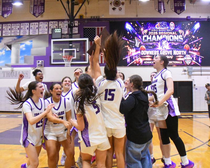Downers Grove North’s girls’ basketball team celebrates with the 4A regional championship plaque after defeating St. Laurence High School on Thursday Feb. 19, 2026, held at Downers Grove North High School.