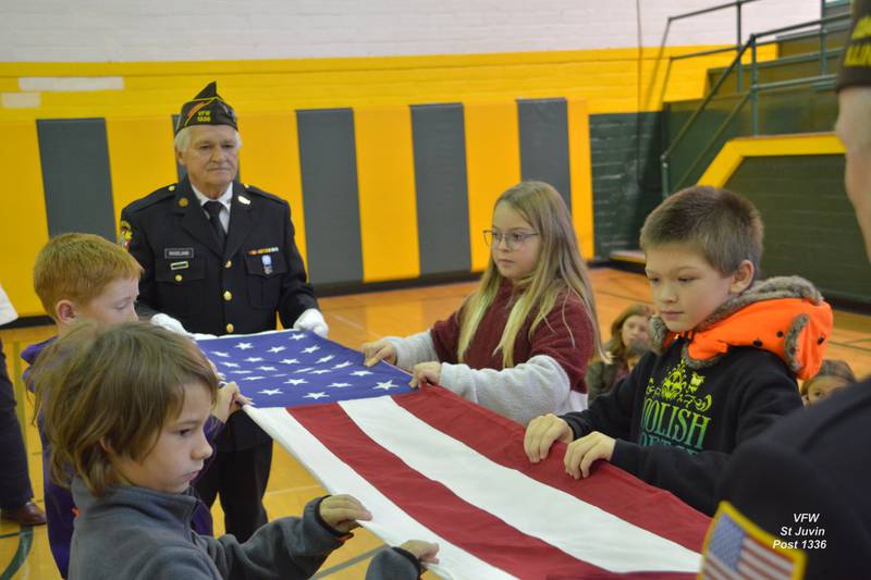 Students assist Post members in folding the flag.