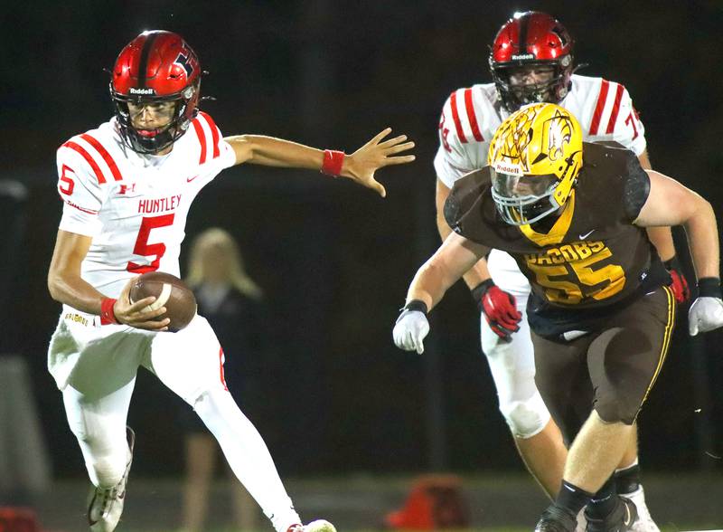 Huntley’s Malik Carter scrambles with the ball as Jacobs’ Lucas Retzler, right, closes in for a tackle in varsity football at Jacobs High School in Algonquin on Friday, Sept. 26, 2025.