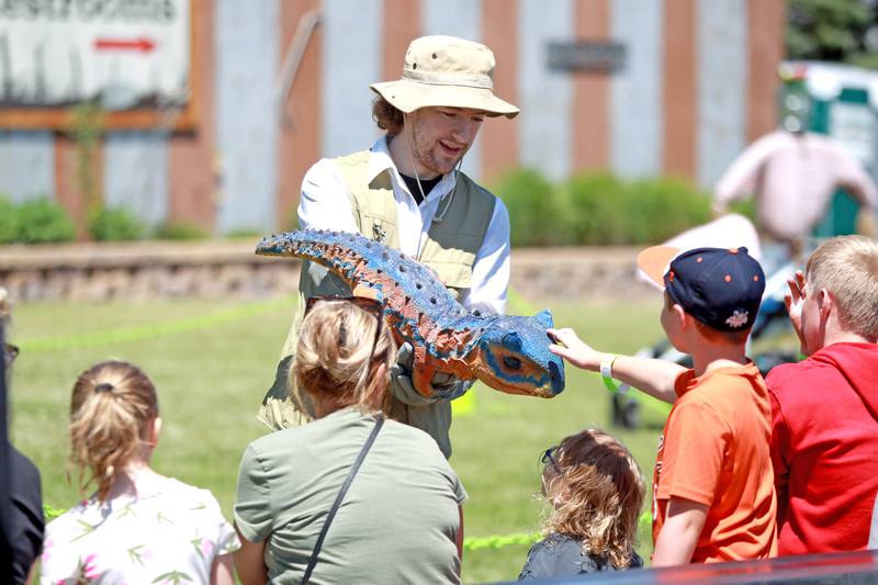 Ashton Cox carries a baby dinosaur during a dinosaur training session as part of the Dino Farm Adventure at Kuipers Family Farm in Maple Park on Thursday, May 30, 2024. The Dino Farm Adventure will be at Kuipers until June 16.