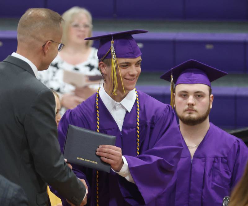 Serena High School graduate Beckham Massier accepts his diploma from superintendent Rich Favire as classmate Tyler Moore (right) watches during the Serena High School Class of 2026 commencement ceremony on Saturday, May 23, 2026 at Serena High school.