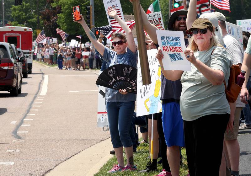 Protesters chant and wave flags along Sycamore Road Saturday, June 14, 2025, during a No Kings rally at Hopkins Park in DeKalb. The group was protesting the policies of President Donald Trump and his administration.