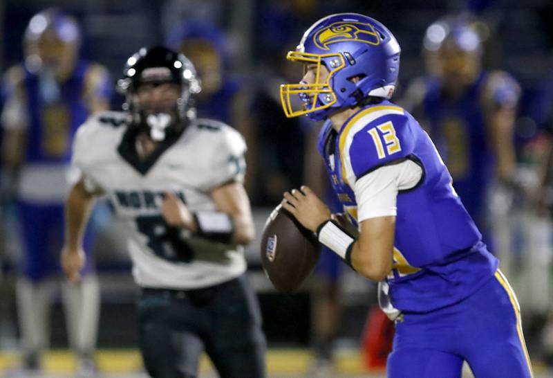 Johnsburg's Carter Block looks to pass as Woodstock North's Michael Pintor runs towards him during a Kishwaukee River Conference football game on Friday, Sept. 26, 2025, at Johnsburg High School.