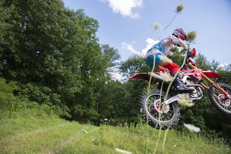 Cody Barnes soars over a hill Thursday, August 4, 2022 while training on a course near Fenton. Barnes will be traveling overseas later this month to participate in an international motocross competition.