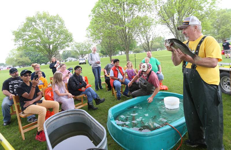 Former Illinois Departmen of Natural Resources fish biologist Kenny Clodfelter holds a largemouth bass while showing different kind of Illinois fish during the twenty-third annual Kids Fishing Expo on Saturday, May 13, 2023 at Baker Lake in Peru.