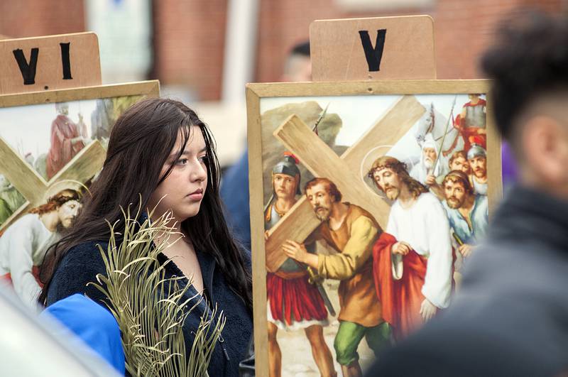 Parishioners follow behind displaying placards with illustrations of the individual stations on Friday in Sterling.