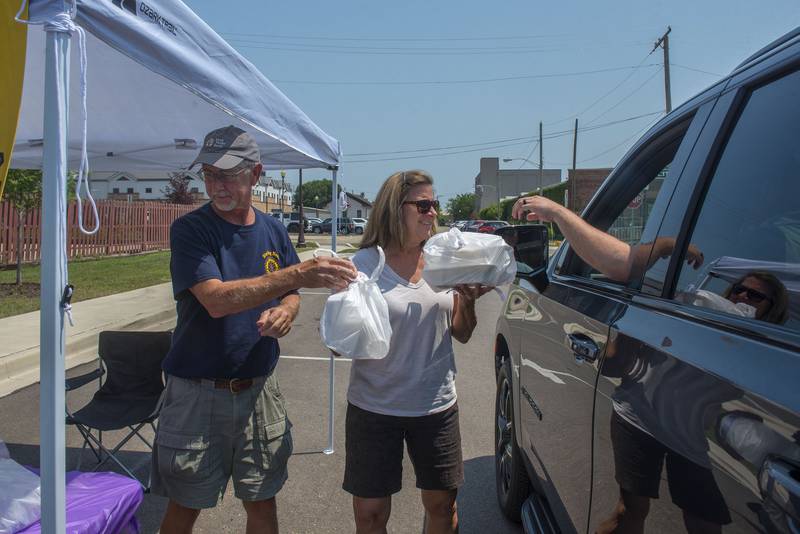 Russ Spitzer and Melody Munson hand out meals Tuesday during a joint effort between the Sterling Noon and Rock Falls Rotary Clubs for a broil and boil fundraiser. The clubs sold sweet corn and pork chop meals to help fund their programs. The two teamed up last year during the pandemic to great success.