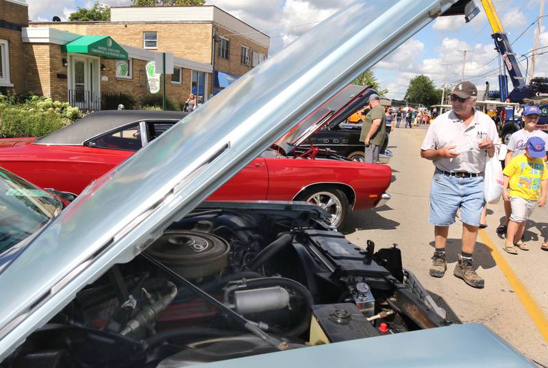 Visitors get a peak at some of the engines in the classic cars on Elm Street in Sycamore Sunday, July 31, 2022, during the 22nd Annual Fizz Ehrler Memorial Car Show. Most of downtown Sycamore was filled with classic cars for the show.