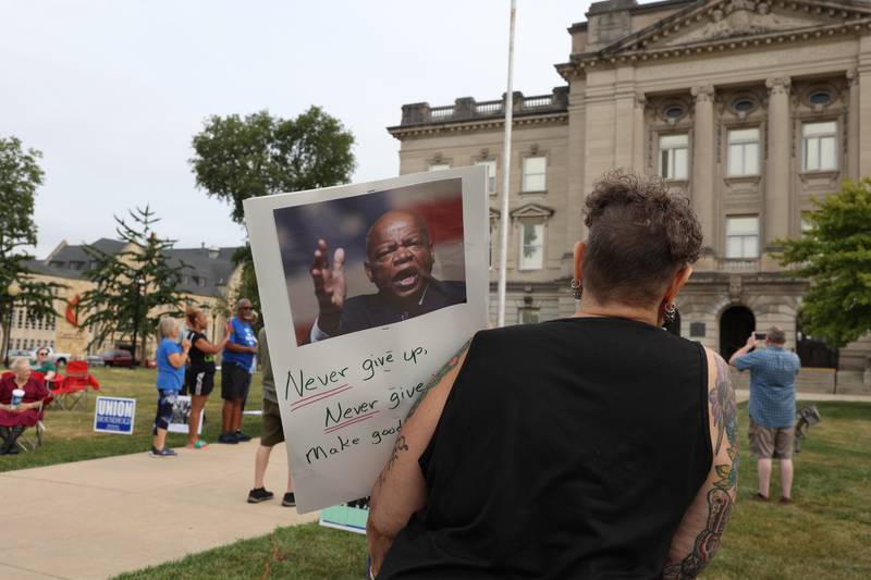A protester holds a sign quote the late civil rights leader and congressman John Lewis during a "Good Trouble Lives On" rally held in Kankakee as part of a national day of peaceful protests on Thursday, July 17, 2025.
