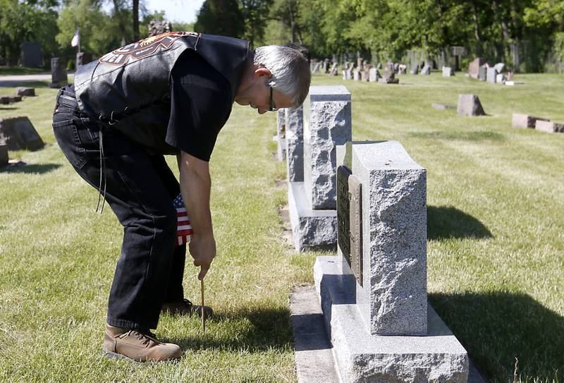 Volunteer Bruce Preston places a flag as he volunteers help former members of Johnsburg VFW Post 11496, place flags Friday, May 26, 2023, at the graves of over 150 veterans in St. John the Baptist Cemetery, in Johnsburg.