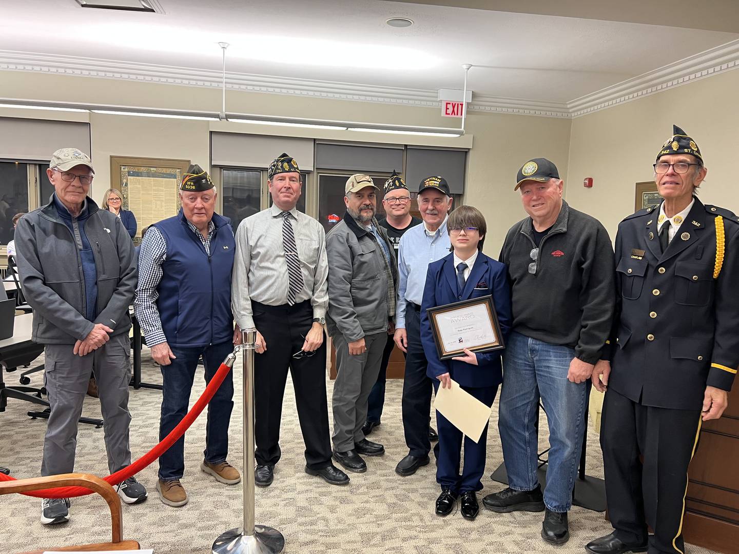 Student Hugo Rodriguez takes a photo with veterans after receiving a Spirit of St. Charles Award during a City Council meeting on Jan. 20, 2026.