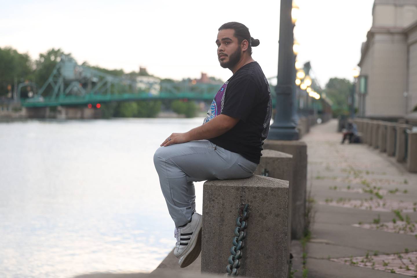 Uxmar Torres sits along the Des Plaines River in downtown Joliet on Tuesday June 4, 2024. Uxmar who has a degree in creative writing has showed his poetry and spoken word in dozens of cities across the United States.
