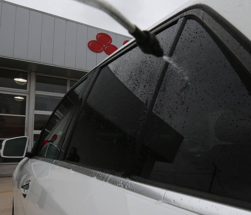 Workers at Cody Burroughs State Farm in La Salle wash down a vehicle using hydrogen peroxide and vinegar the day after the Carus Chemical fire on Thursday, Jan. 12, 2023 in La Salle.