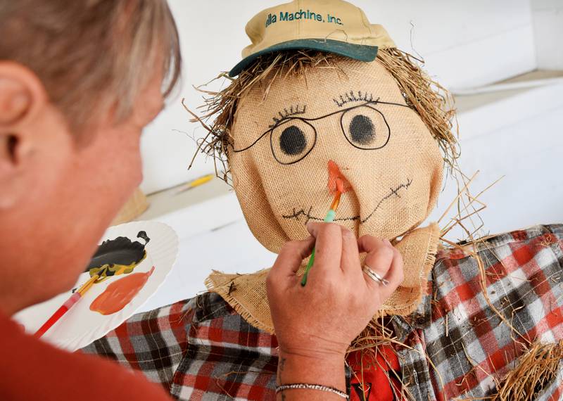 Carrie Vander Weerdt, advertising director for Newton News, paints a nose on a scarecrow on Oct. 9 outside the Newton News building. The scarecrow is one of many on display at the Newton Arboretum & Botanical Gardens through Oct. 14, which is also the day of the Fall Festival. The festival runs from 10 a.m. to 2 p.m.