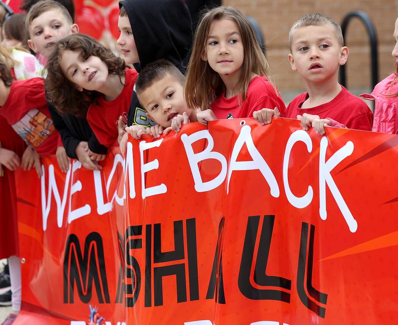 First grade classmates of Marshall Morong, 7, peer down Lincoln Avenue Monday, May 5, 2025, outside of Hinckley-Big Rock Elementary School, as they await his arrival for his first day back following months waiting for, and eventually receiving, heart transplant surgery at Lurie Children’s Hospital of Chicago. Morong arrived in style in a Tesla Cybertruck donated for use by Telsa of Naperville, along with an escort by Hinckley and Big Rock first responders.