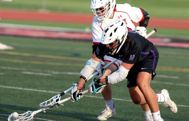 Huntley’s Trace Tedesco, back, races Hampshire’s Chase Lorbiecki for the ball in varsity lacrosse at Huntley Thursday night.