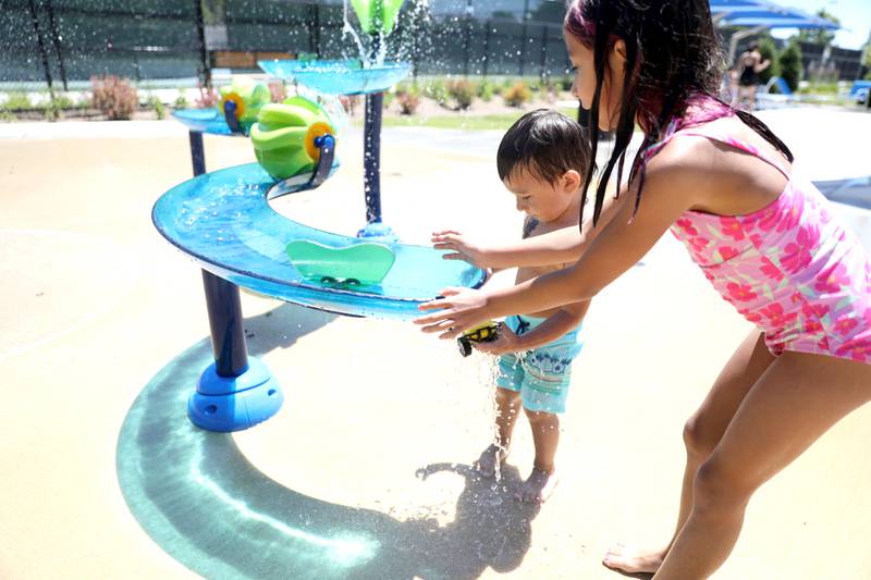 Siblings Angel, 2, and Evelyn Flores, 7, play in the water at the Downers Grove Park District’s Adventure Falls Sprayground at McCollum Park on Friday, June 14, 2024.
