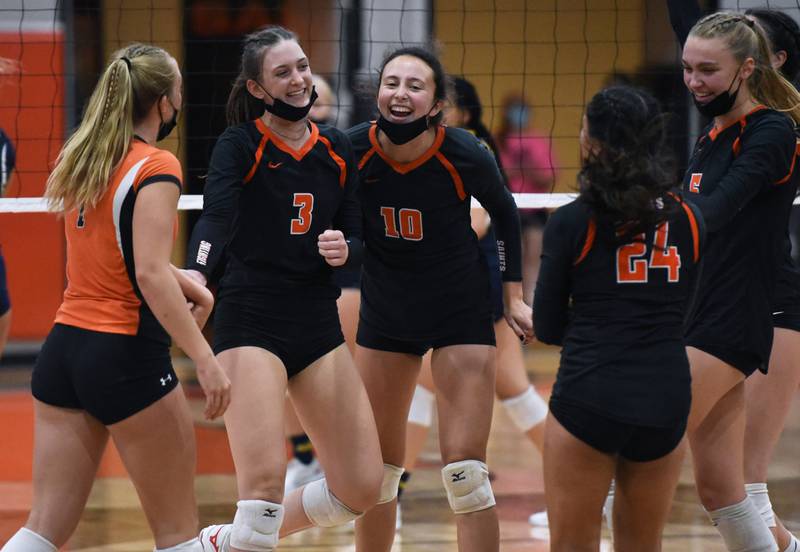 St. Charles East's Kate Goudreau (3) and Isabella Mosquera (10) celebrate a point with teammates before defeating Neuqua Valley during Wednesday's girls volleyball match in St. Charles.