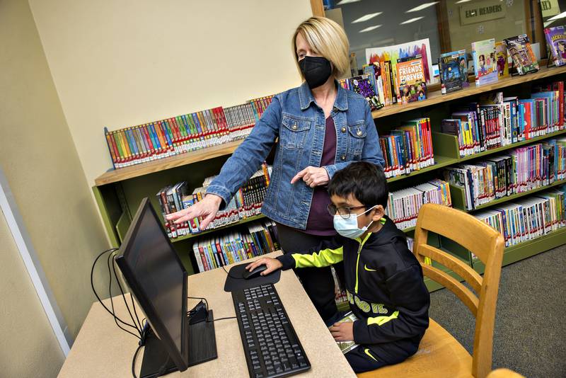 Dixon librarian Kathleen Schaefer gestures while working with Sarthak Agrawal, 7, on a a coding program at the library. The library was able to offer the club due to COVID money that paid for the program and equipment.