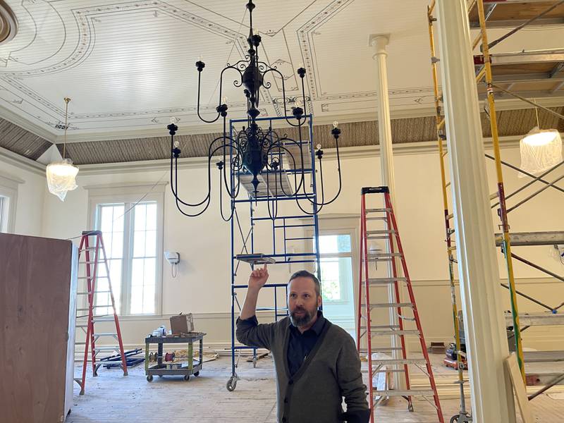 Woodstock City Planner Darrell Moore explains the history behind the iron chandelier hanging in the new banquet hall at the Old Courthouse and Sheriff's House on May 25, 2023, in Woodstock