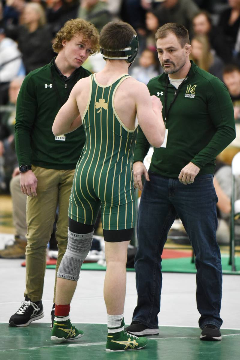 Bishop McNamara wrestling coach Jake Kimberlin, right, and assistant coach Caleb Magruder, left, talk with Blake Arseneau during a timeout in Arsenau's 132-pound third-place match of the IHSA Class 1A Coal City Sectional.