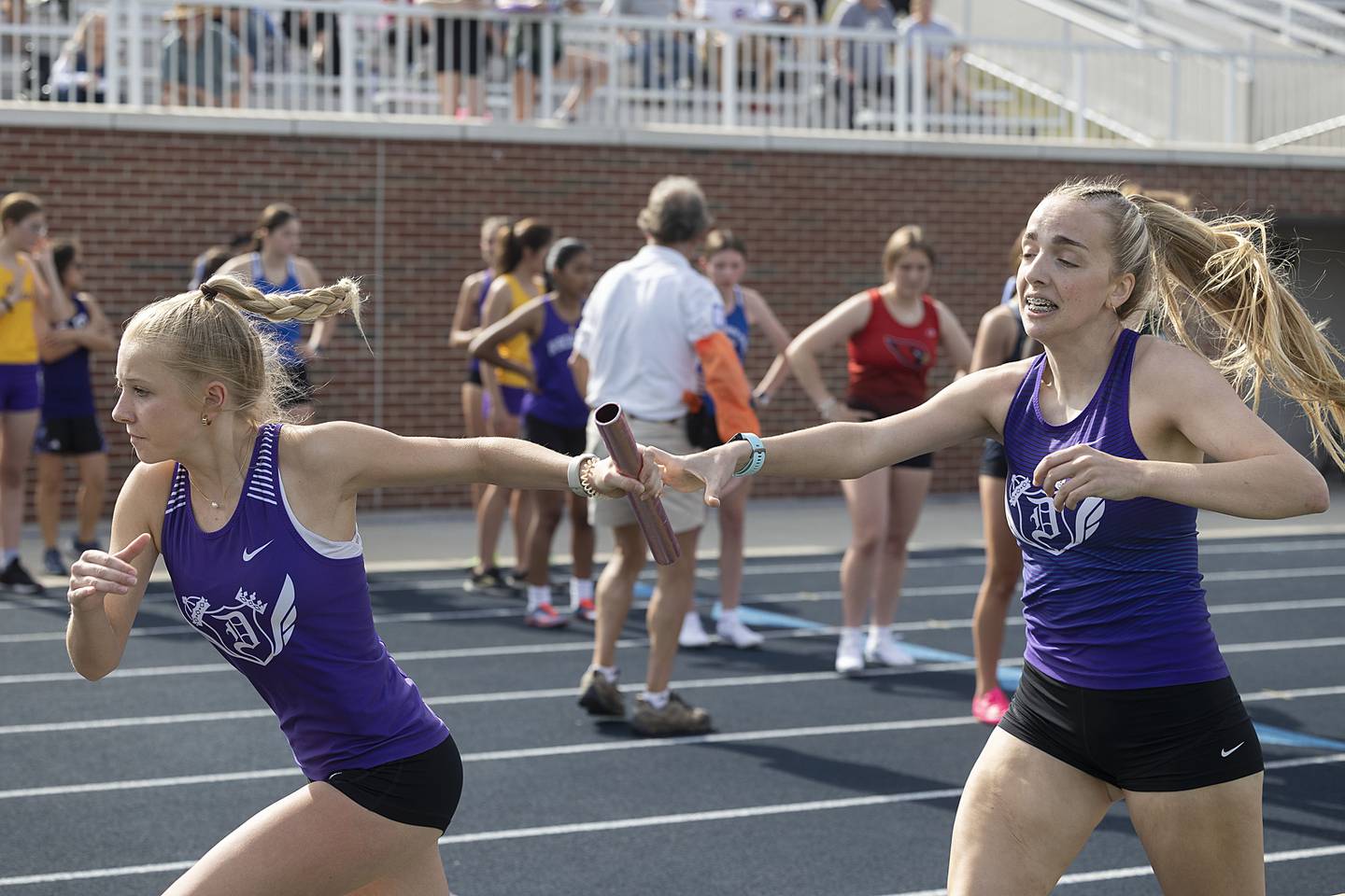 Dixon’s Kait Knipple hands the baton off to Kate Boss in the 4x800 Thursday, May 11, 2023 at the class 2A Sterling girls track sectionals.