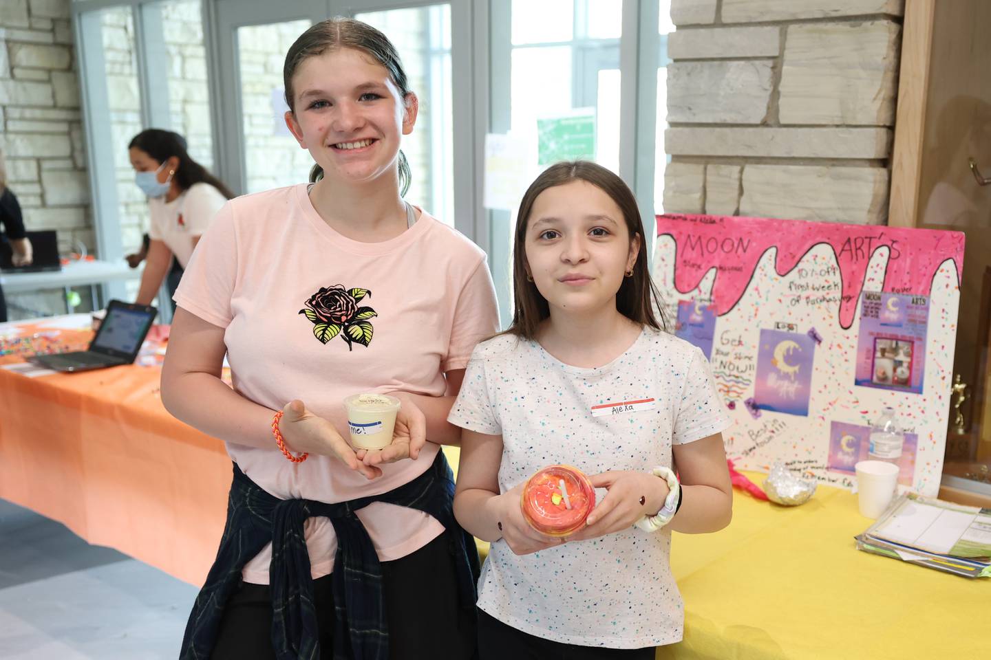 Melanie Bell, left, and Alexa Rodriguez hold their slim product at their slim business Moon Arts at the Laraway 70C 5th Grade Business Expo. Friday, May 13, 2022, in Joliet.