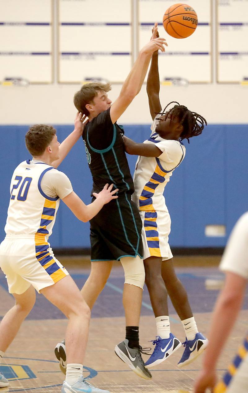 Woodstock North's AJ Cohen (center) pass out of a double team by Johnsburg's Josh Kaunas (left) and Jarrel Albea during a Kishwaukee River Conference boys basketball game on Monday, Dec. 15, 2025, at Johnsburg High School.