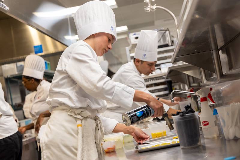 Joliet Junior College culinary arts program.  taken in 2023 of our then-student competition team during a practice. JJC PR said: I think they illustrate the action and dynamics of the training kitchens at City Center campus.