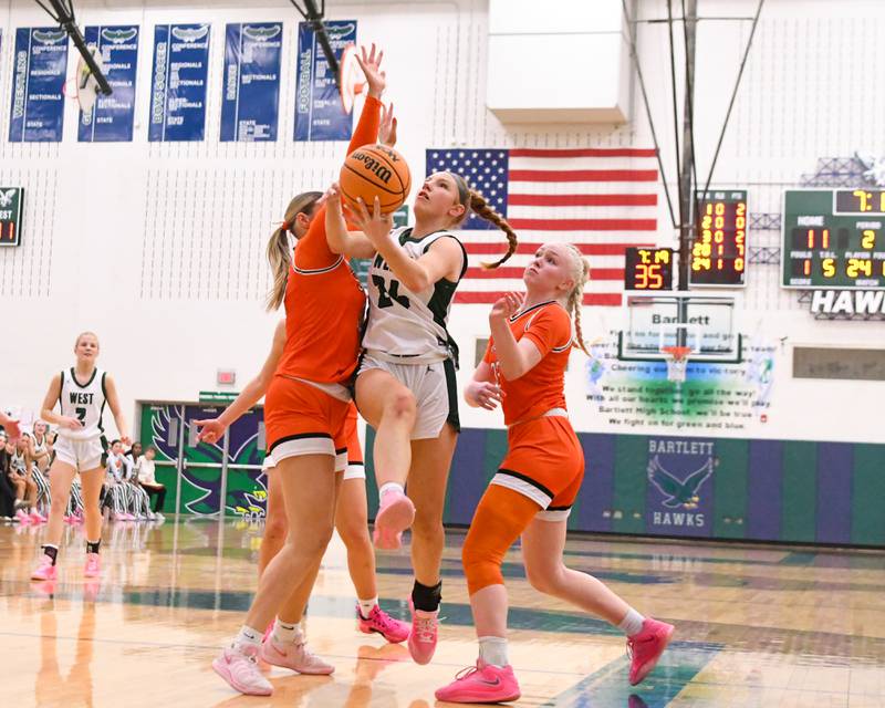 Glenbard West's Sophia Evans, center, goes up for a shot while being defended by St. Charles East teammates Stella Trask, left, and Addison Schilb, during the 4A Sectional championship game on Thursday Feb. 26, 2026, held at Bartlett High School.