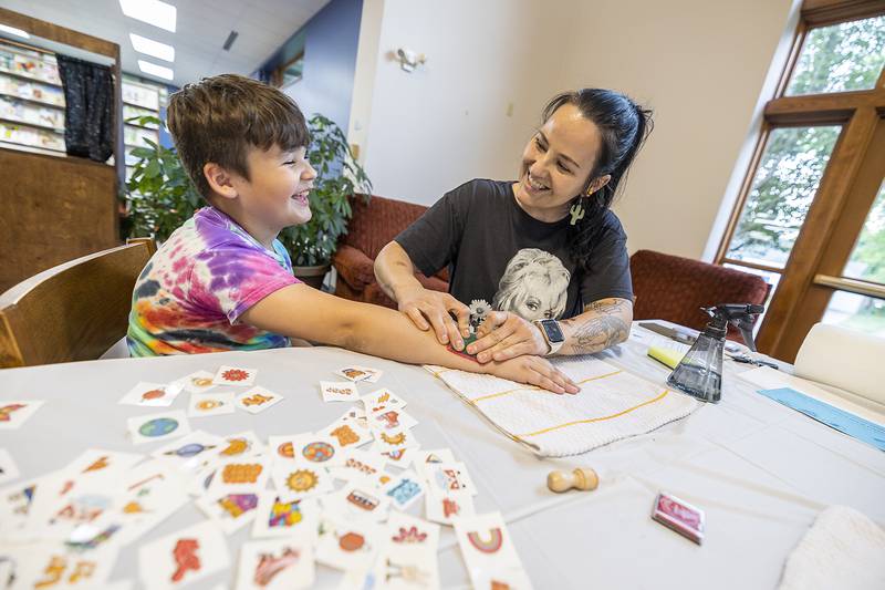 Marlyce Miller of Dixon gives son Ben Albarran, 8, a temporary tattoo Wednesday, June 25, 2025, at the Odell Library in Morrison. The Whiteside County United Way and LIFE (Literacy of Fun for Everyone) sponsored Dolly's Book Bash at the library. The celebration honors Dolly Parton's Imagination Library and the transformative power of reading.
