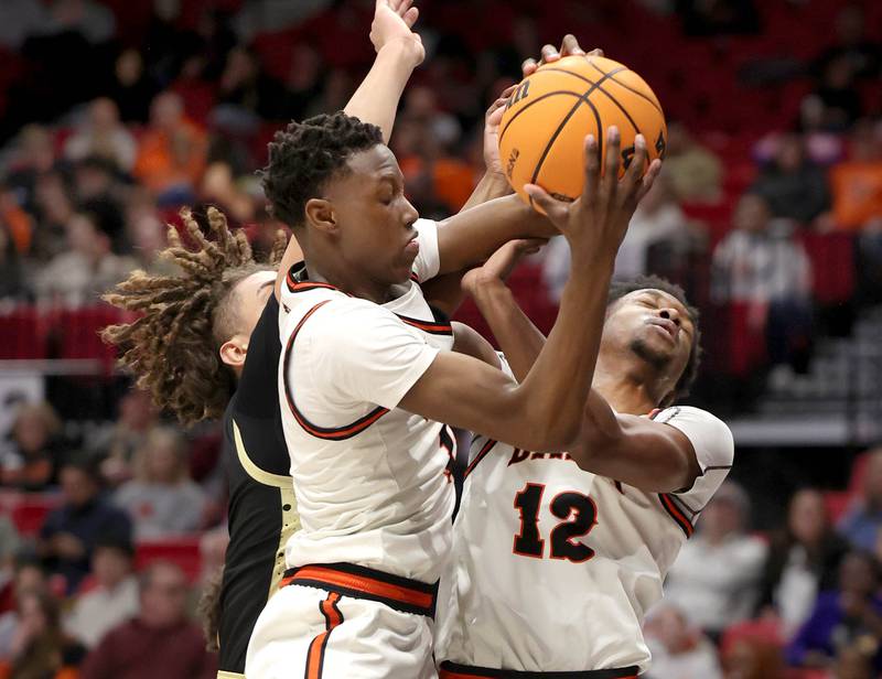 DeKalb's Gabriel Crump (left) Sycamore's Josiah Mitchell and DeKalb's Derrion  Straughter go after a rebound Friday, Jan. 30, 2026, during the FNBO Challenge at the Convocation Center at Northern Illinois University in DeKalb.