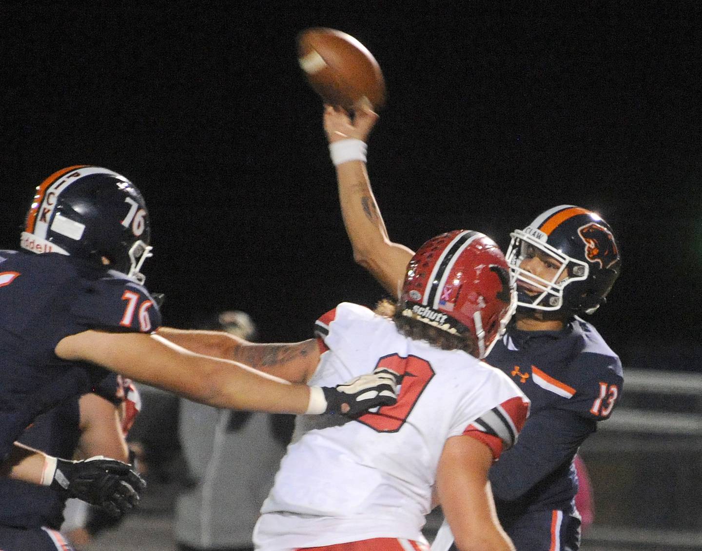 Oswego quarterback Cruz Ibarra (13) throw under pressure from Yorkville defender Andrew laurich (9) during a varsity football game at Oswego High School on Friday, Oct. 21, 2022.