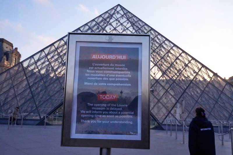 A board advises opening delays outside the pyramid of the Louvre museum as workers at the Louvre will vote to go on strike or continue talks with the government after months of mounting pressure on the world's most visited museum, Monday, Dec. 15, 2025 in Paris. (AP Photo/Michel Euler)
