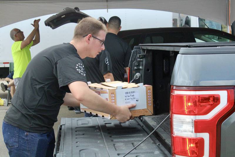 Trevor Johnson with the U.S. Army Recruiting Station in Dixon helps load a 22-pound of peaches into a vehicle during the distribution for the annual Kiwanis Club of Dixon peach sale at Dixon High School.