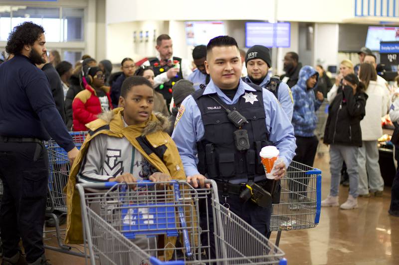 Joliet Police Officer Jorge Trujillo (right) prepares to shop with a child during the 36th annual Santa's Cops event on Saturday, Dec. 6, 2025, at Walmart, 401 Illinois Route 59, in  Shorewood.