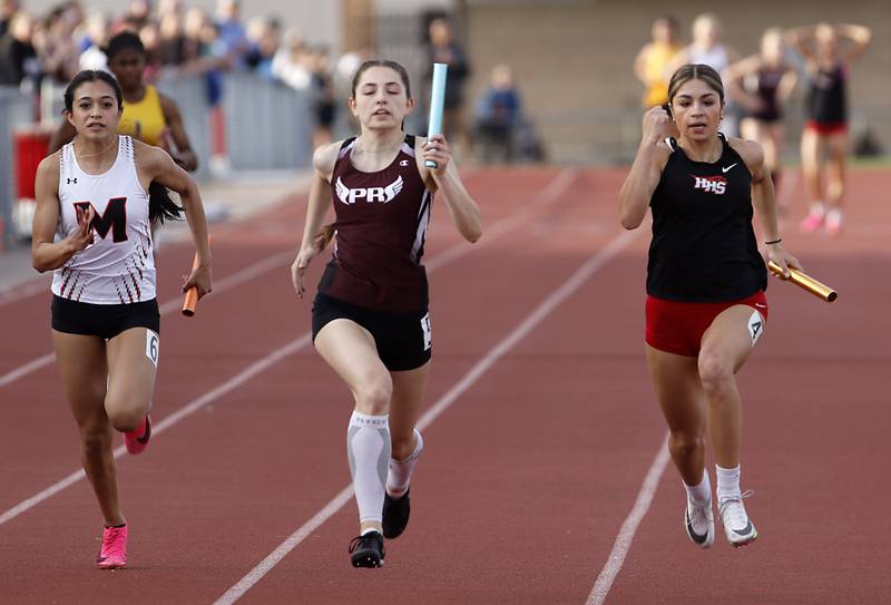 McHenry’s Kelly Huerta, Prairie Ridge’s Kaitlyn Harmke, and Huntley’s Victoria Evtimov race to the finish line in the 4x100 meter relay  Friday, May 5, 2023, during the Fox Valley Conference Girls Track and Field Meet at Huntley High School.