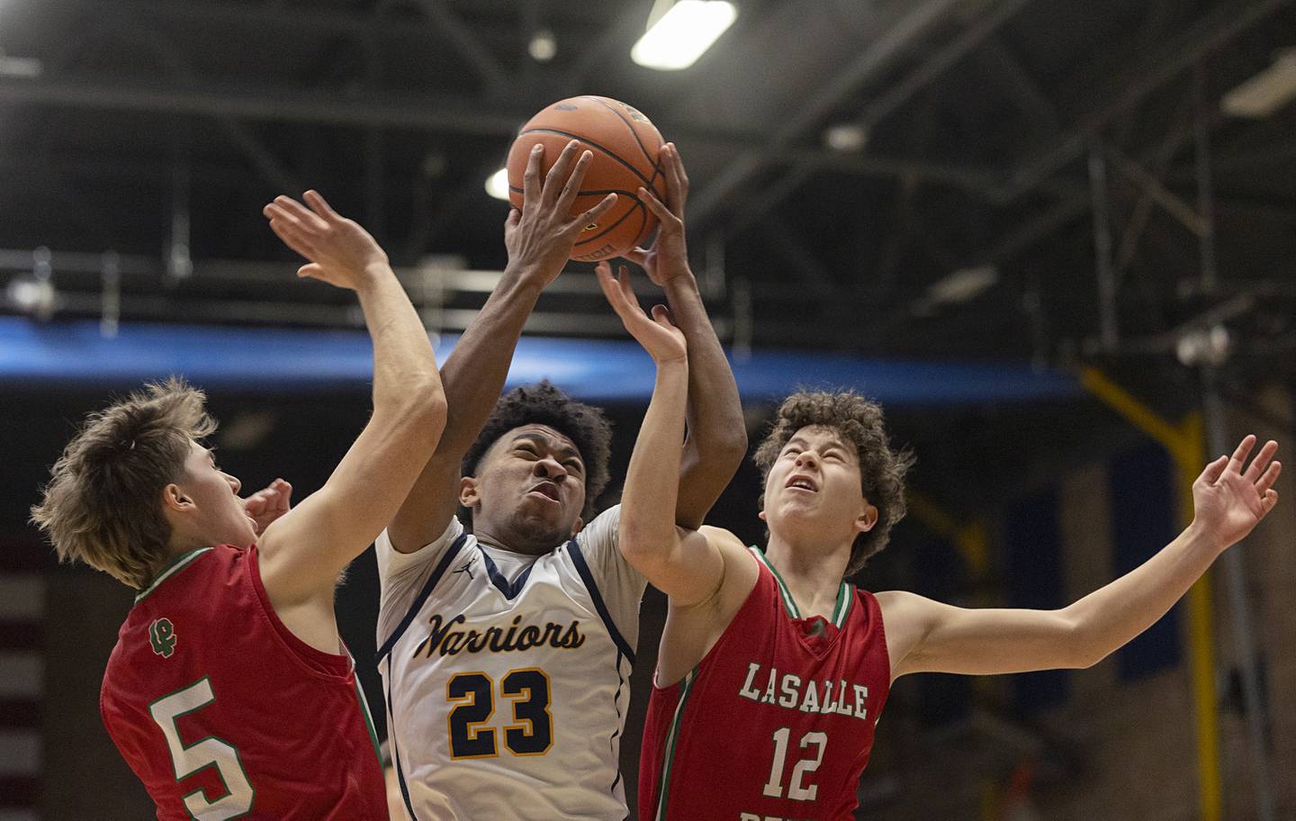 Sterling’s Kaedon Phillips hauls in a rebound against LaSalle-Peru’s Seth Adams (left) and Michael Hartman Friday, Feb. 23, 2024 during a class 3A regional final at Sterling High School.