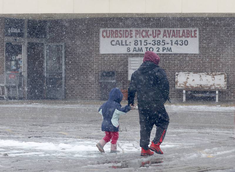 A man and his daughter walks through the falling snow towards La Michoacana on West Elm Street in McHenry on Wednesday, Jan. 25, 2023. Snow fell throughout the morning, leaving a fresh blanket of snow in McHenry County.